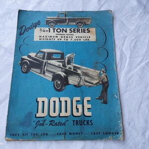 Puede incluir: Un anuncio vintage para los camiones Dodge 3/4-1 Ton Series. El anuncio presenta un fondo azul con un logotipo Dodge blanco y el texto "Job-Rated" trucks. El anuncio también presenta una imagen en blanco y negro de un camión Dodge con un hombre de pie junto a él.