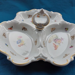 May include: White porcelain serving dish with three sections and a handle. The dish is decorated with floral patterns in various colours and gold trim. The edges have a scalloped design.