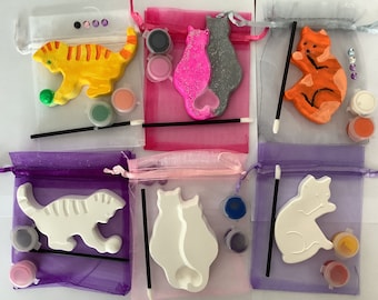 May include: Six paint-your-own cat figurines in individual organza bags. Each bag includes paints, a paintbrush, and rhinestones. The cats are in various poses, including sitting, standing, and playing with a ball.