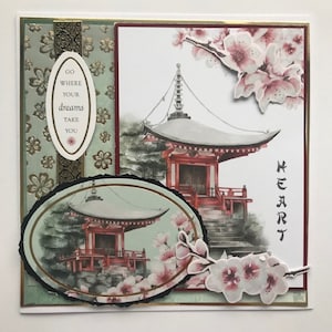 May include: A greeting card with a watercolor illustration of a Japanese temple with cherry blossoms. The card has a green and gold patterned background with a quote that reads "Go where your dreams take you".