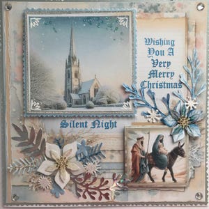 以下が含まれることがあります： 手作りのクリスマスカード。冬の教会の風景、"Wishing You A Very Merry Christmas"と"Silent Night"の文字。青と白の花と葉の装飾、そして聖家族の小さな画像が特徴です。