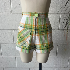 Peut inclure: Short en jean à taille haute à carreaux, dans les tons vert, jaune et blanc. Le short a une grande poche plaquée sur le côté gauche.