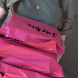 May include: A stack of pink mailing envelopes with the word "Jackie" printed on the top envelope.