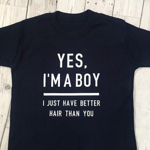 Puede incluir: Una camiseta azul marino con texto blanco que dice "YES, I'M A BOY I JUST HAVE BETTER HAIR THAN YOU"