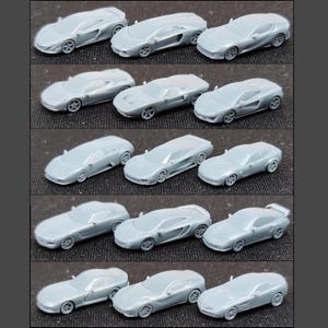 Puede incluir: Una colección de coches de juguete grises en miniatura, cada uno con un diseño único. Los coches están dispuestos en filas, mostrando varios modelos con detalles como ruedas y contornos de la carrocería. La imagen está tomada desde arriba.