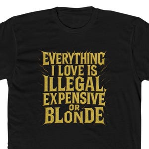 May include: Black t-shirt with gold text that reads "EVERYTHING I LOVE IS ILLEGAL, EXPENSIVE OR BLONDE." The text is in a bold, stylized font. The shirt is a crew neck style.