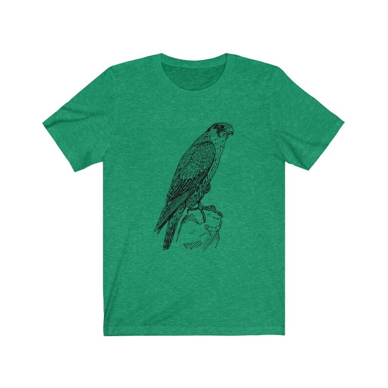 May include: A green t-shirt featuring a black and white illustration of a falcon perched on a rock.