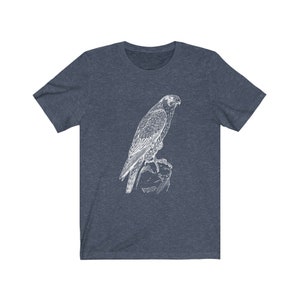 May include: A dark blue t-shirt featuring a white outline drawing of a falcon perched on a rock.