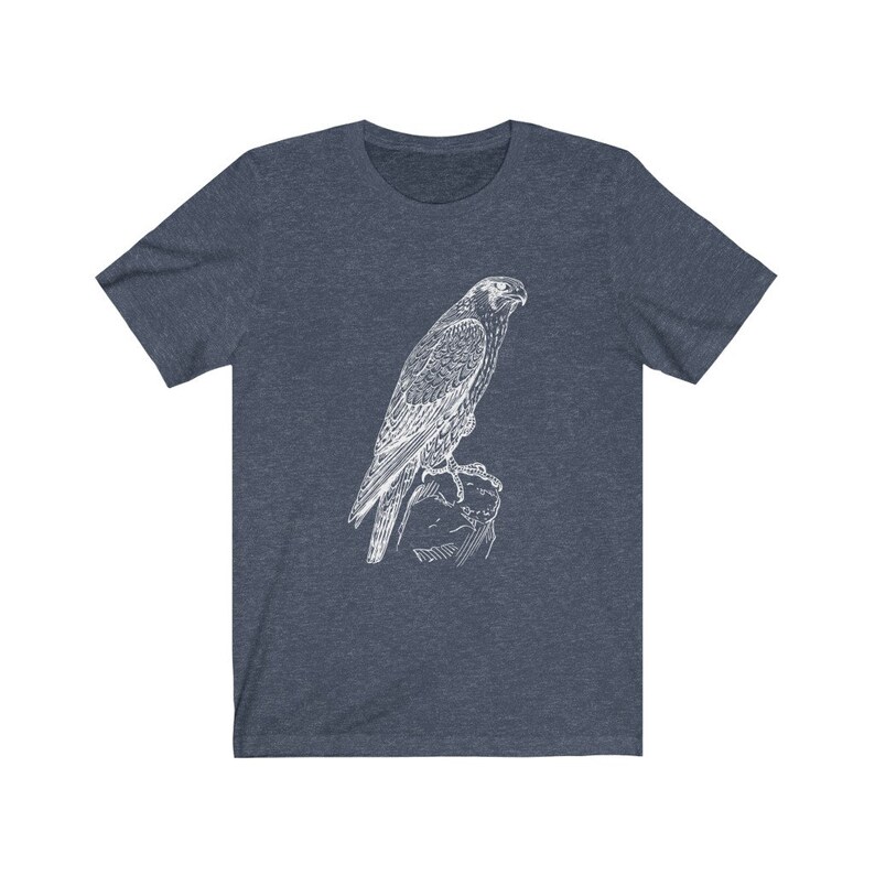 May include: A dark blue t-shirt featuring a white outline drawing of a falcon perched on a rock.