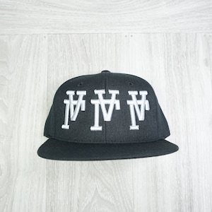 May include: A black baseball cap with a white "MMM" logo embroidered on the front.