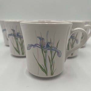 May include: Set of six white ceramic coffee mugs with a floral design featuring blue and purple irises on a green stem.