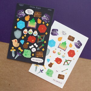 May include: Two sheets of stickers with a black and white background. The stickers feature a variety of images related to a game night theme, including dice, treasure chests, swords, and potions. The text on the stickers reads "Game Night", "Can I loot the body?", and "You can try".