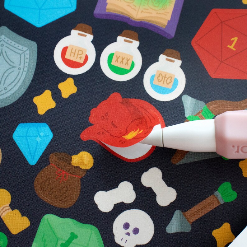 May include: A close-up of a red dragon sticker being applied to a black background with various other stickers, including a blue diamond, a brown bag, a green potion bottle with the text "XXX", a blue potion bottle with the text "OTC", a yellow bone, a green gem, and a white skull.