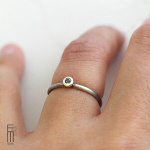 May include: A silver ring with a small, round, green gemstone set in the center.