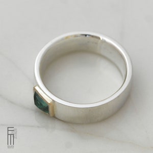 May include: A silver band ring with a square green gemstone set in a gold band.