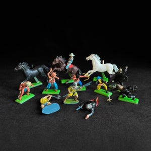 May include: A collection of small plastic toy figurines featuring mounted riders on black, brown, and white horses, alongside various standing and kneeling warriors in colorful painted outfits, each attached to a small rectangular base.