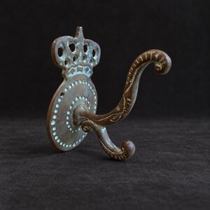ヴィンテージ風の装飾的なダブルウォールフック、透かし彫りの金属製バックプレート、古びた風合いのコート＆ハットフック
