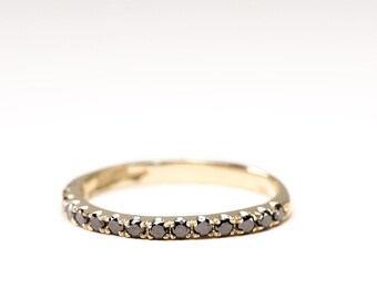 May include: A thin gold band ring with a row of small black diamonds.