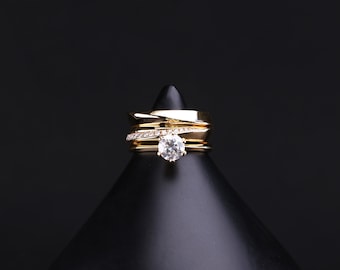 Op de afbeelding: Een gouden ring met een grote, heldere, ronde diamant. De ring staat op een zwarte displaystandaard.