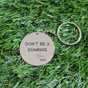 May include: Silver keychain with a round tag that says "Don't be a Dumbass. Love, Dad" on a green background.