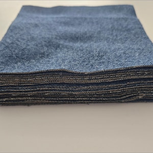 May include: A stack of blue denim fabric squares. The fabric is folded neatly and the edges are visible.