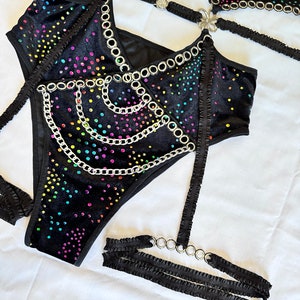 K&ouml;nnte beinhalten: Schwarzes Samt-Dessous-Set mit Regenbogen-Strassteinen und silbernen Kettenakzenten. Das Set beinhaltet einen BH, einen Slip und ein Strumpfband.