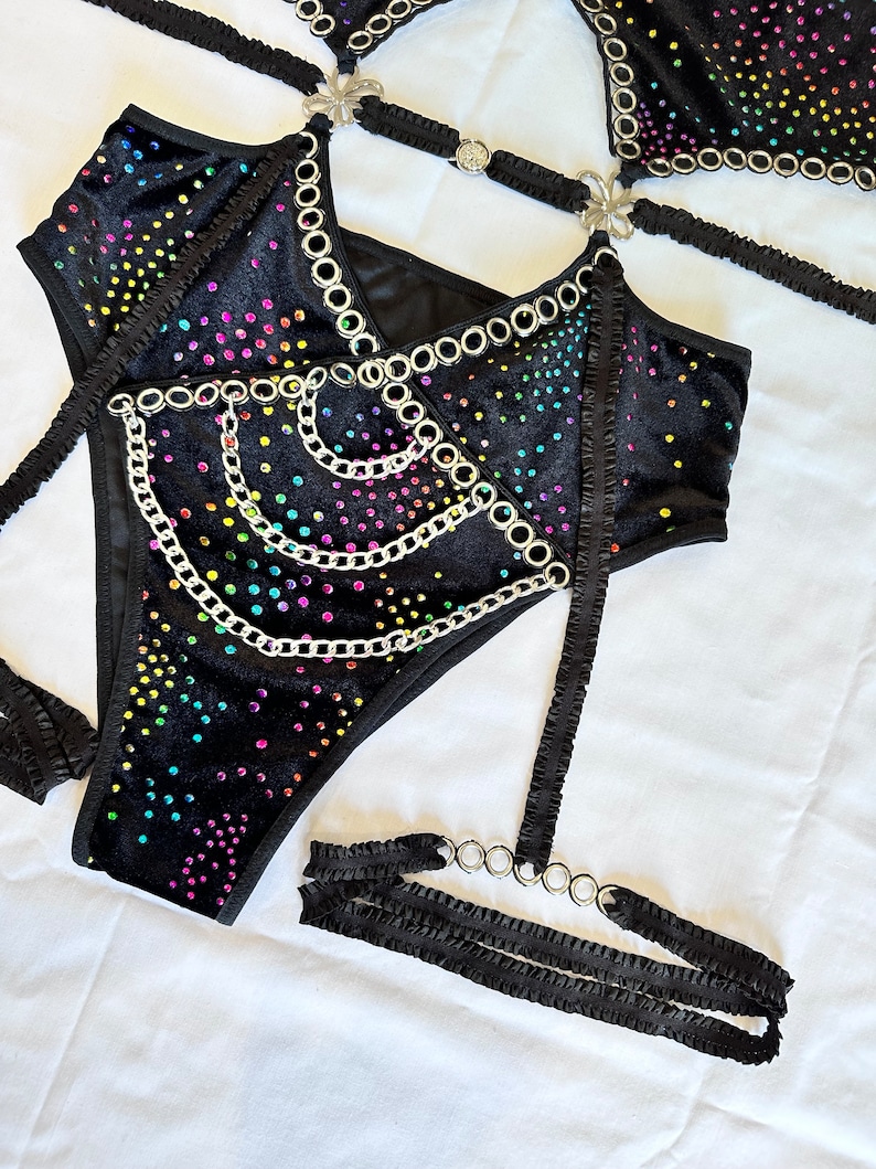 K&ouml;nnte beinhalten: Schwarzes Samt-Dessous-Set mit Regenbogen-Strassteinen und silbernen Kettenakzenten. Das Set beinhaltet einen BH, einen Slip und ein Strumpfband.