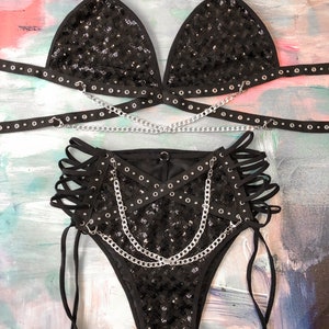 May include: Black sequined lingerie set with silver chains and grommets. The set includes a triangle bra, high-waisted bottoms, and a chain belt.
