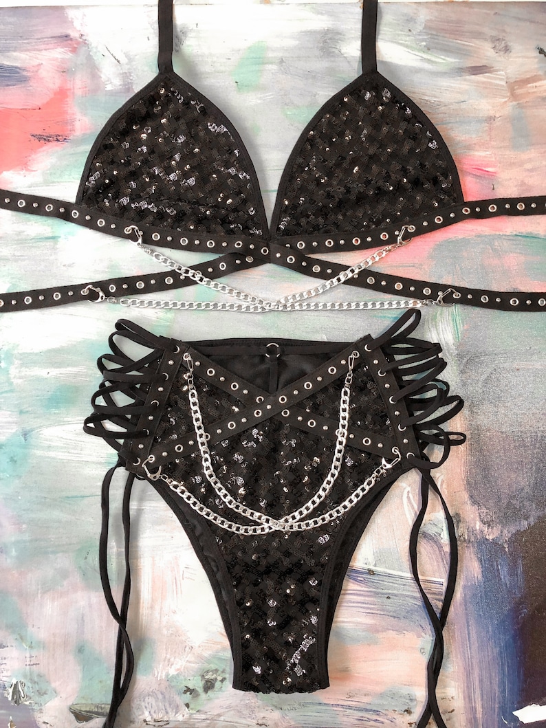 May include: Black sequined lingerie set with silver chains and grommets. The set includes a triangle bra, high-waisted bottoms, and a chain belt.