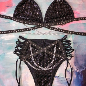 May include: Black sequined lingerie set with a triangle bra and high-waisted bottoms. The set features multiple straps and chains.