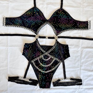 K&ouml;nnte beinhalten: Schwarzes Samt-Dessous-Set mit silbernen Ketten und bunten Strasssteinen. Das Set beinhaltet einen BH, einen Body und Str&uuml;mpfe.