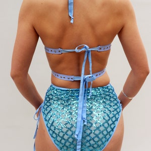 Puede incluir: Un top y una parte inferior de bikini azul claro con un patr&oacute;n de lentejuelas. El top tiene tirantes ajustables y un lazo en la espalda. La parte inferior tiene cintura alta y lazos en los lados.