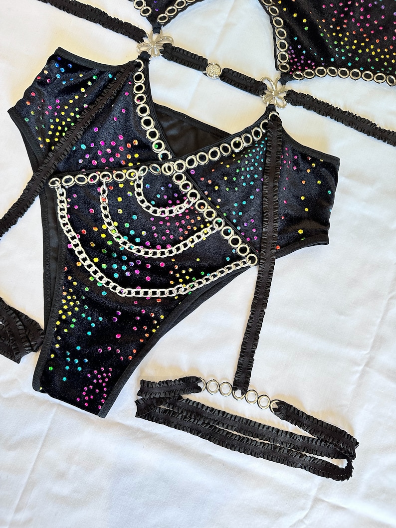 K&ouml;nnte beinhalten: Schwarzes Samt-Dessous-Set mit Regenbogen-Stra&szlig;steinen und silbernen Kettenakzenten. Das Set beinhaltet einen BH, einen Slip und ein Strumpfband.