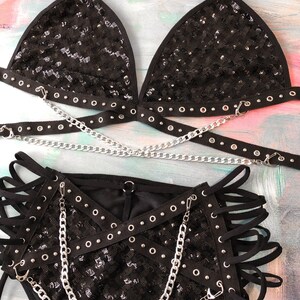 May include: Black sequined lingerie set with silver chains and grommets. The set includes a triangle bra and high-waisted bottoms.
