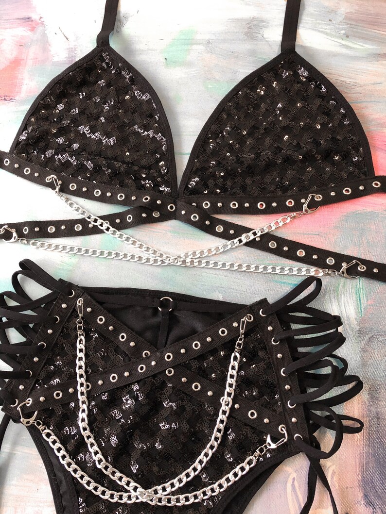 May include: Black sequined lingerie set with silver chains and grommets. The set includes a triangle bra and high-waisted bottoms.