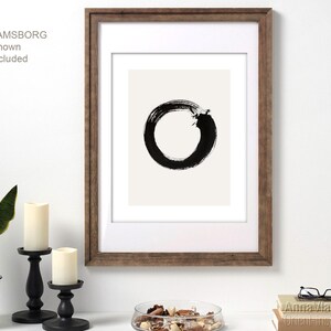 May include: Black and white abstract art print of a circle with a break in it, framed in a brown wood frame. IKEA RAMSBORG frame shown is not included.