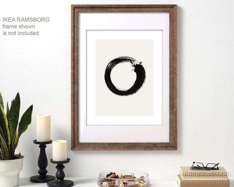 May include: Black and white abstract art print of a circle with a break in it, framed in a brown wood frame. IKEA RAMSBORG frame shown is not included.