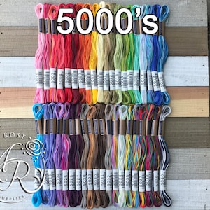 May include: A collection of 40 embroidery floss spools in various colors, including red, orange, yellow, green, blue, purple, brown, and white. The spools are labeled with numbers from 5001 to 5040. The text "5000's" is written in large letters at the top of the image.