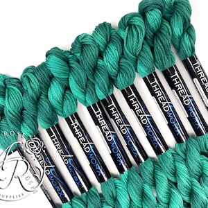 May include: Eight spools of green hand-dyed embroidery floss, each with a black label that reads "THREADWORX Hand-Overdyed Floss 100% Cotton".