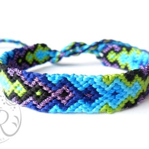 May include: A colorful friendship bracelet with a chevron pattern in shades of blue, green, purple, and black.