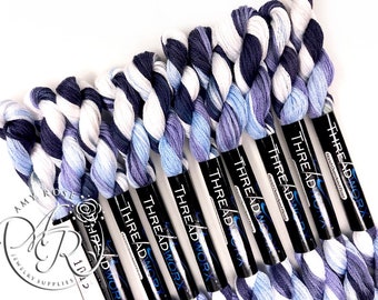 May include: A set of 10 skeins of hand-dyed embroidery floss in shades of blue, white, and black. The floss is wound on black spools with the label "THREADWORX" printed on them.