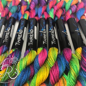May include: Close-up of six spools of rainbow colored embroidery floss. The spools are labeled "THREAD WORX" and "THREADWORA".