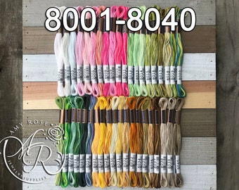 May include: A collection of 40 embroidery floss spools in various colors, including white, pink, green, yellow, and brown. The spools are labeled with numbers from 8001 to 8040.