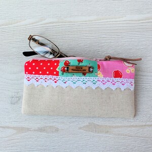 May include: A pink and red patchwork fabric zippered pouch with a white lace trim and a wooden tag that reads "Annie Thornalley".