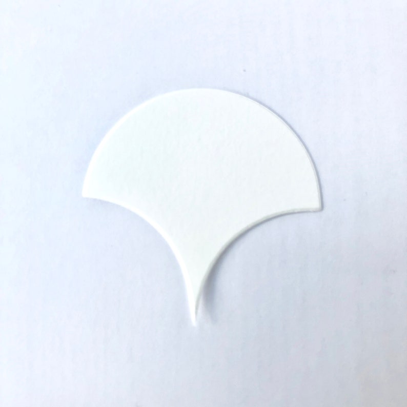Pode incluir: Um azulejo de cer&acirc;mica branco em forma de leque com fundo pontiagudo.