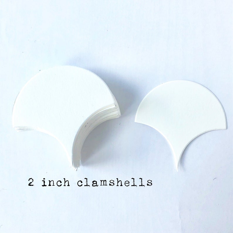 Pode incluir: Uma pilha de conchas de papel brancas, cada uma com um di&acirc;metro de 5 cm. As conchas est&atilde;o dispostas em forma de semic&iacute;rculo, com o texto "2 inch clamshells" escrito abaixo.