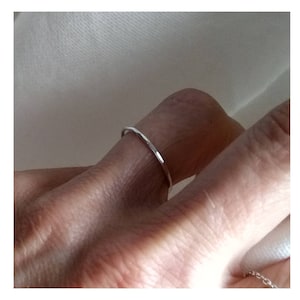 Op de afbeelding: Een dunne zilveren ring gedragen aan een vinger.