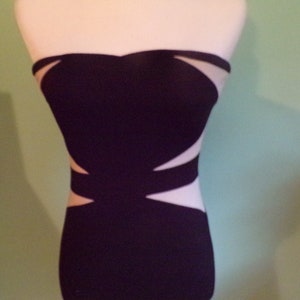 May include: A black strapless dress with a white geometric design. The dress is fitted and has a short length.