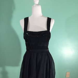 May include: A black sleeveless dress with a sequined bodice and a bubble hem.