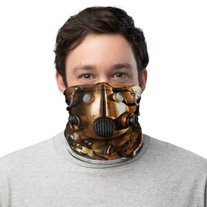 May include: A gold and brown face mask with a steampunk design. The mask has a large, round, metal faceplate with a series of pipes and gears. The faceplate has a large, round, metal eye piece and a smaller, round, metal nose piece.